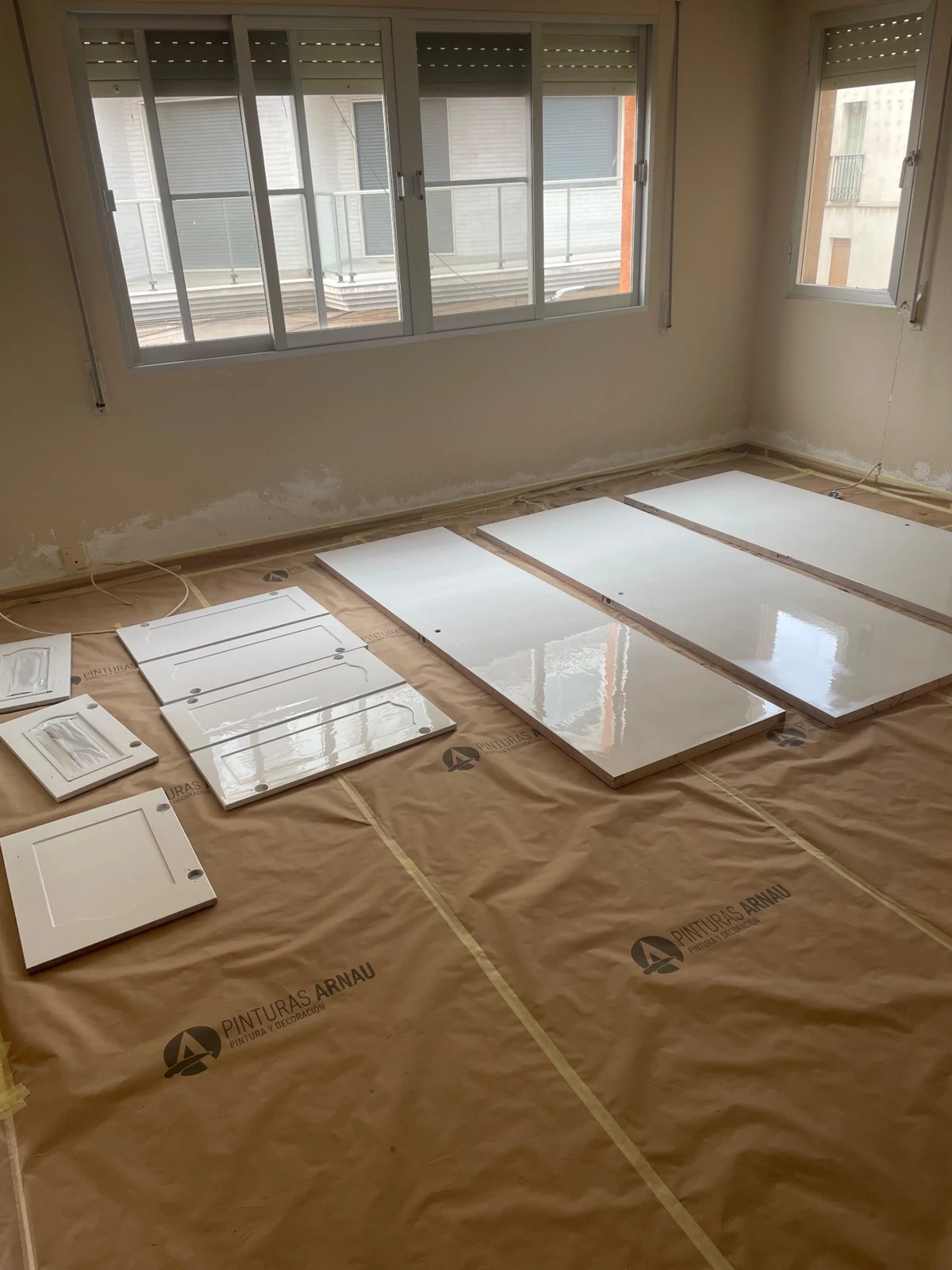 Puertas y frentes de muebles con acabado blanco brillante sobre un suelo protegido